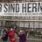 Drei Personen zeigen auf einen großen Banner WIR SIND HERNE