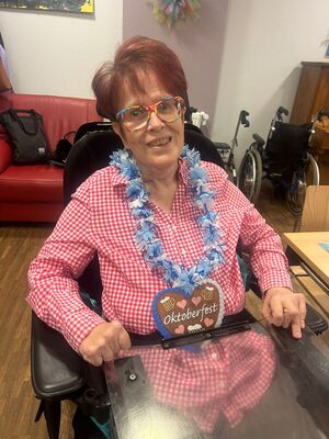 Eine Frau im Rollstuhl mit einem Lebkuchen Herz um den Hals.