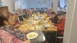 Viele Gäste sitzen an einem langen Tisch und essen.