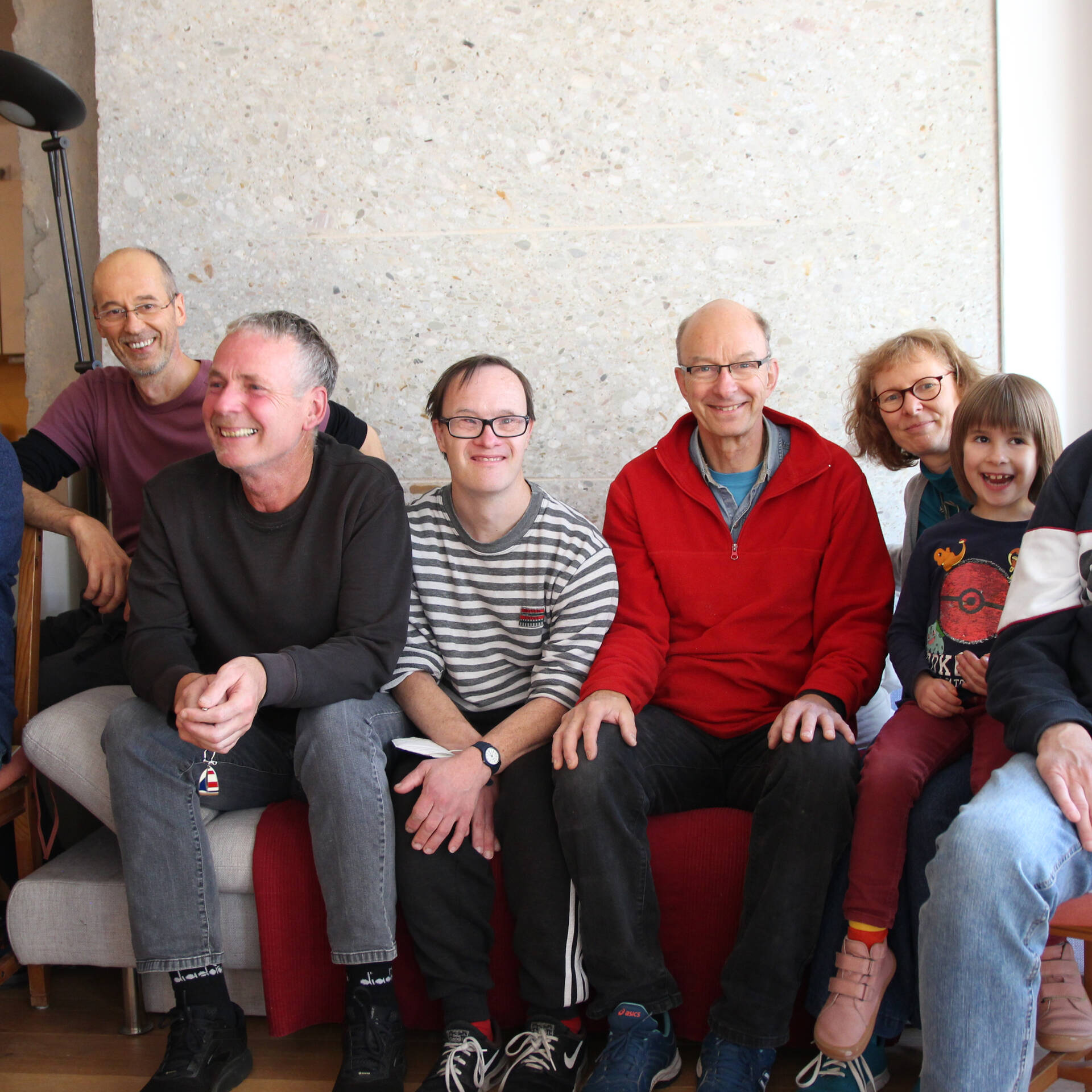 Viele Personen sitzen auf einem Sofa.