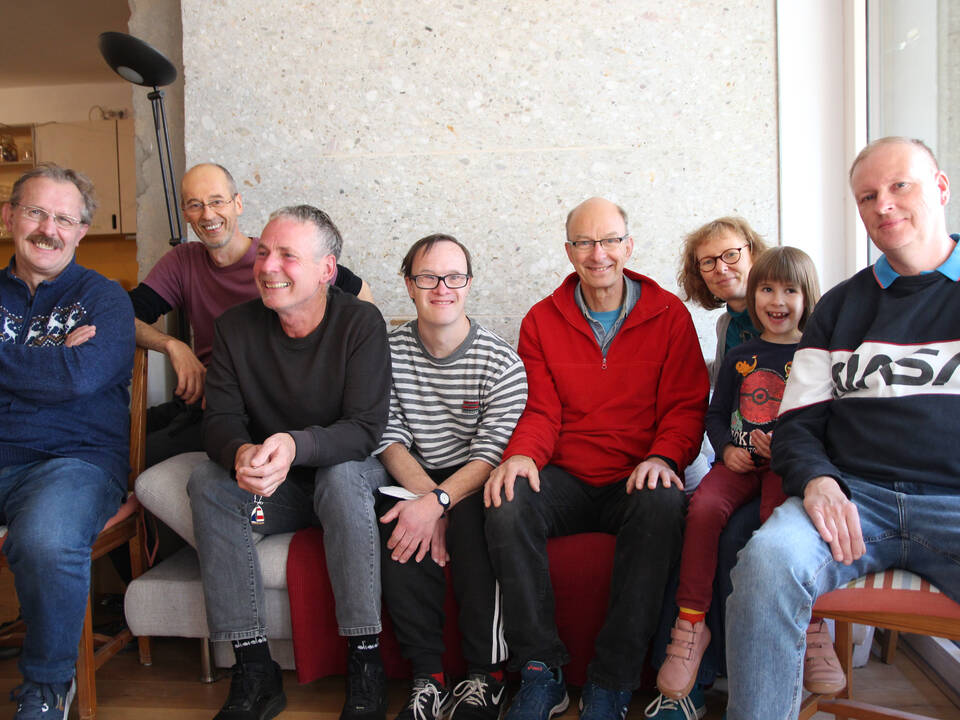 Viele Personen sitzen auf einem Sofa.