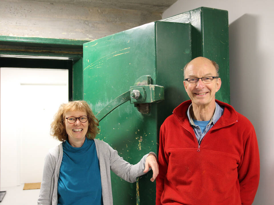 Eine Frau und ein Mann stehen vor einer dicken grünen Stahktüre