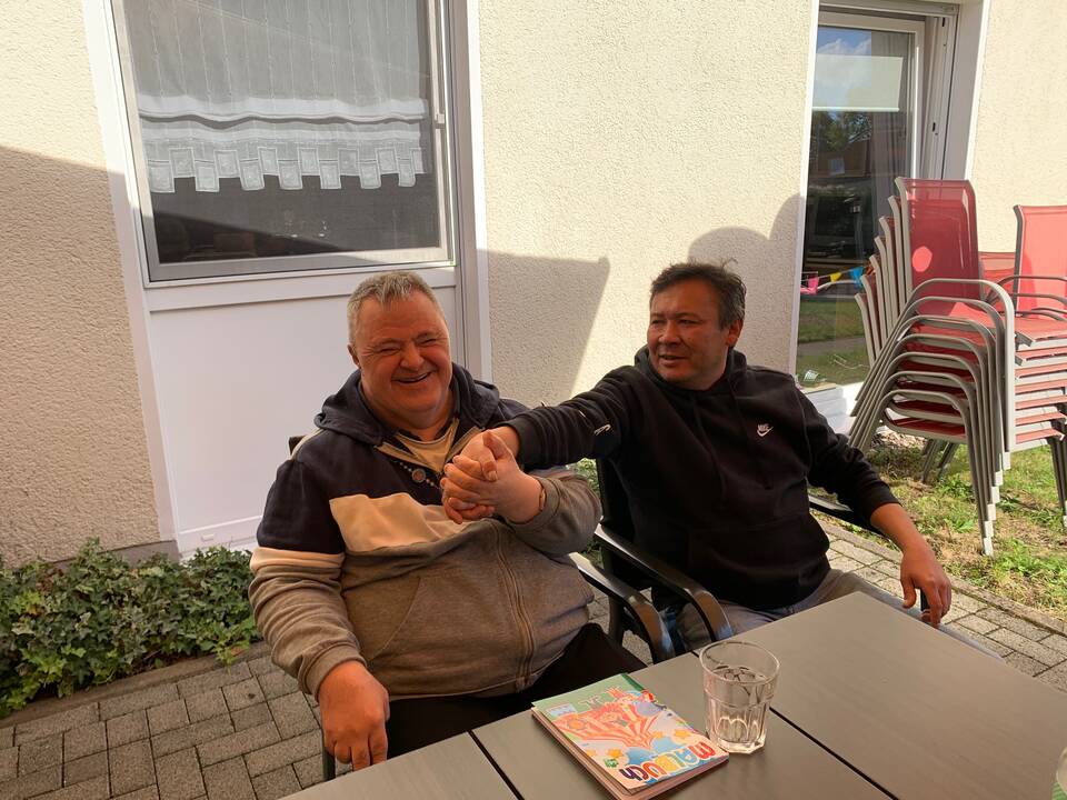 Zwei Personen sitzen draussen und hallten sich die Hand.