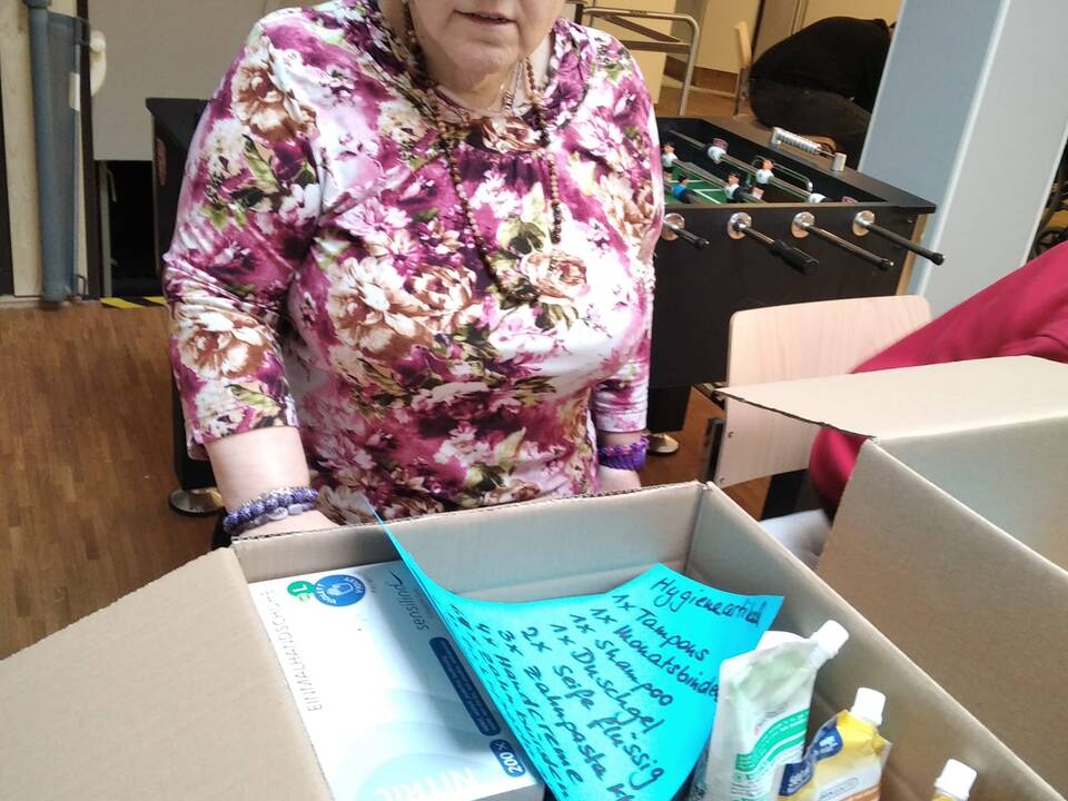 Eine Frau steht vor einem gepackenten Karton.