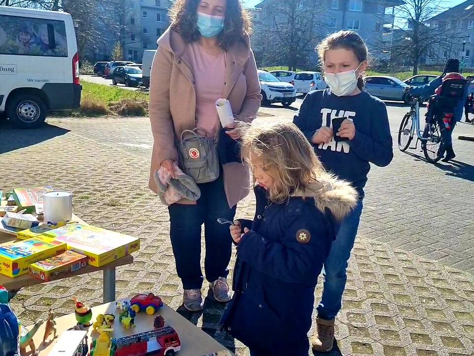 Zwei Kinder und eine Frau vor Spielsachen.