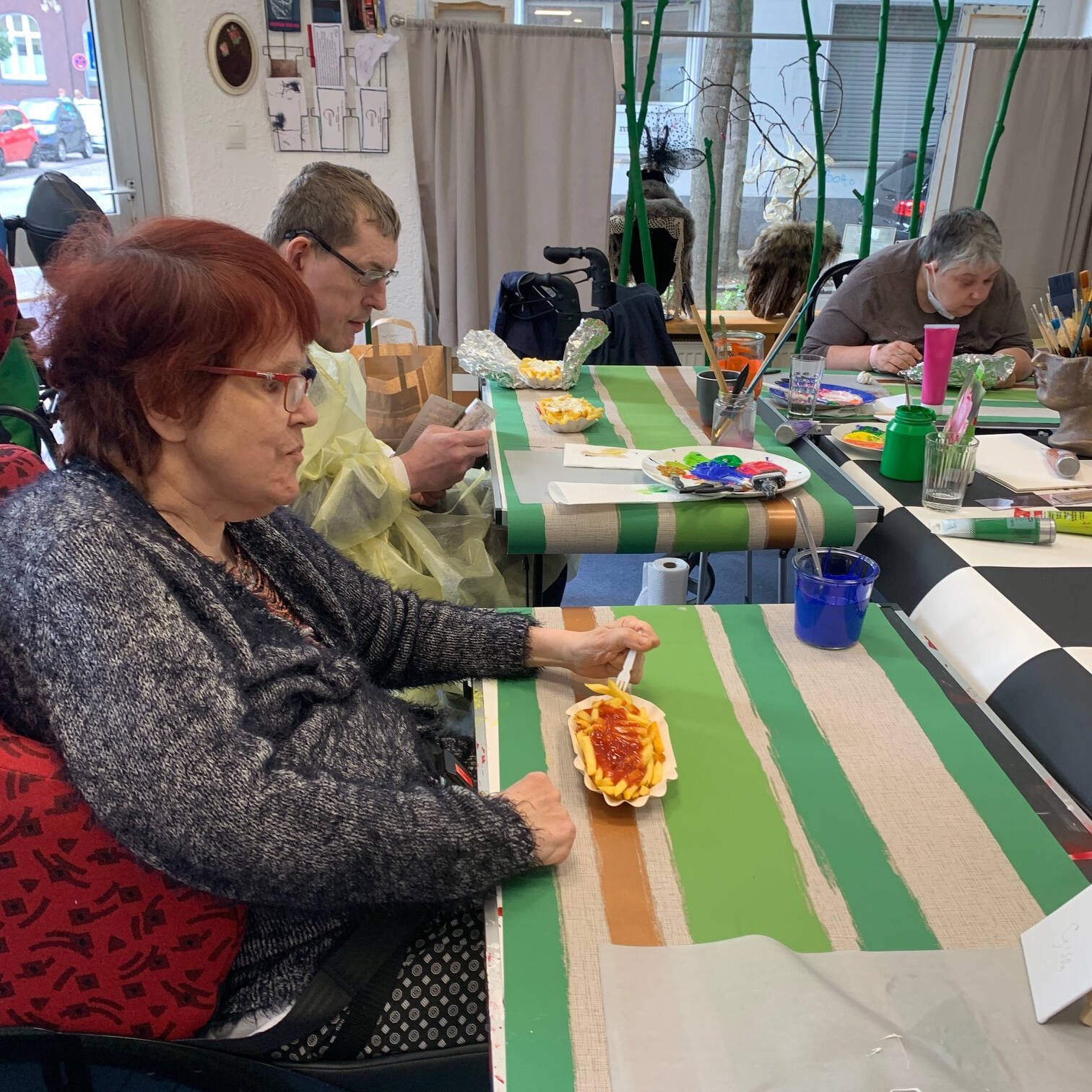 Mehrere Menschen an einem Tisch die mit Farbe arbeiten.