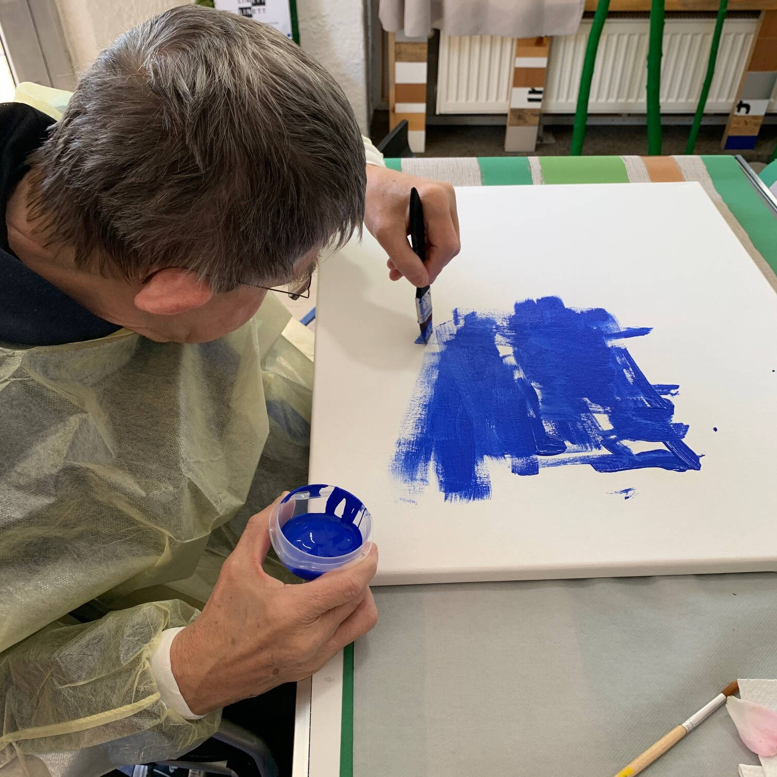 Ein Herr malt auf weißem Untergrund.