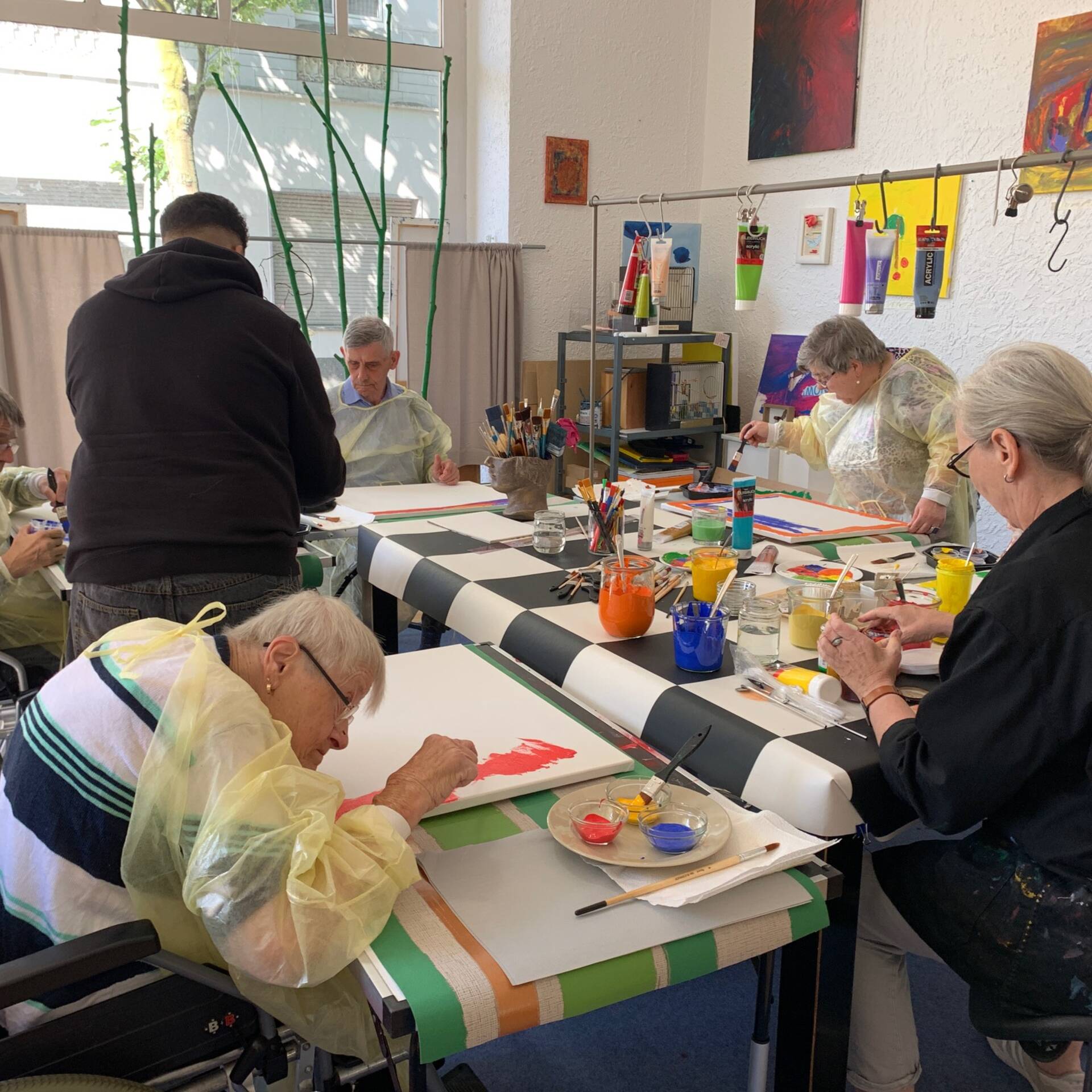 Mehrere Menschen sitzen um einen Tisch und malen.