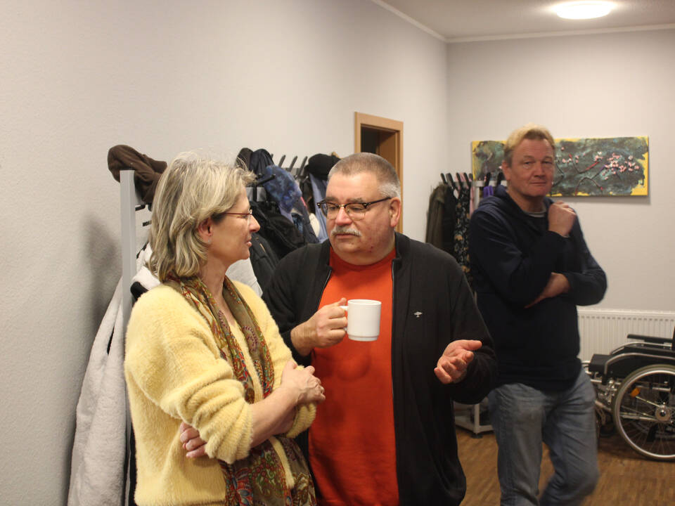 Drei Personen stehen in einem kleinen Raum