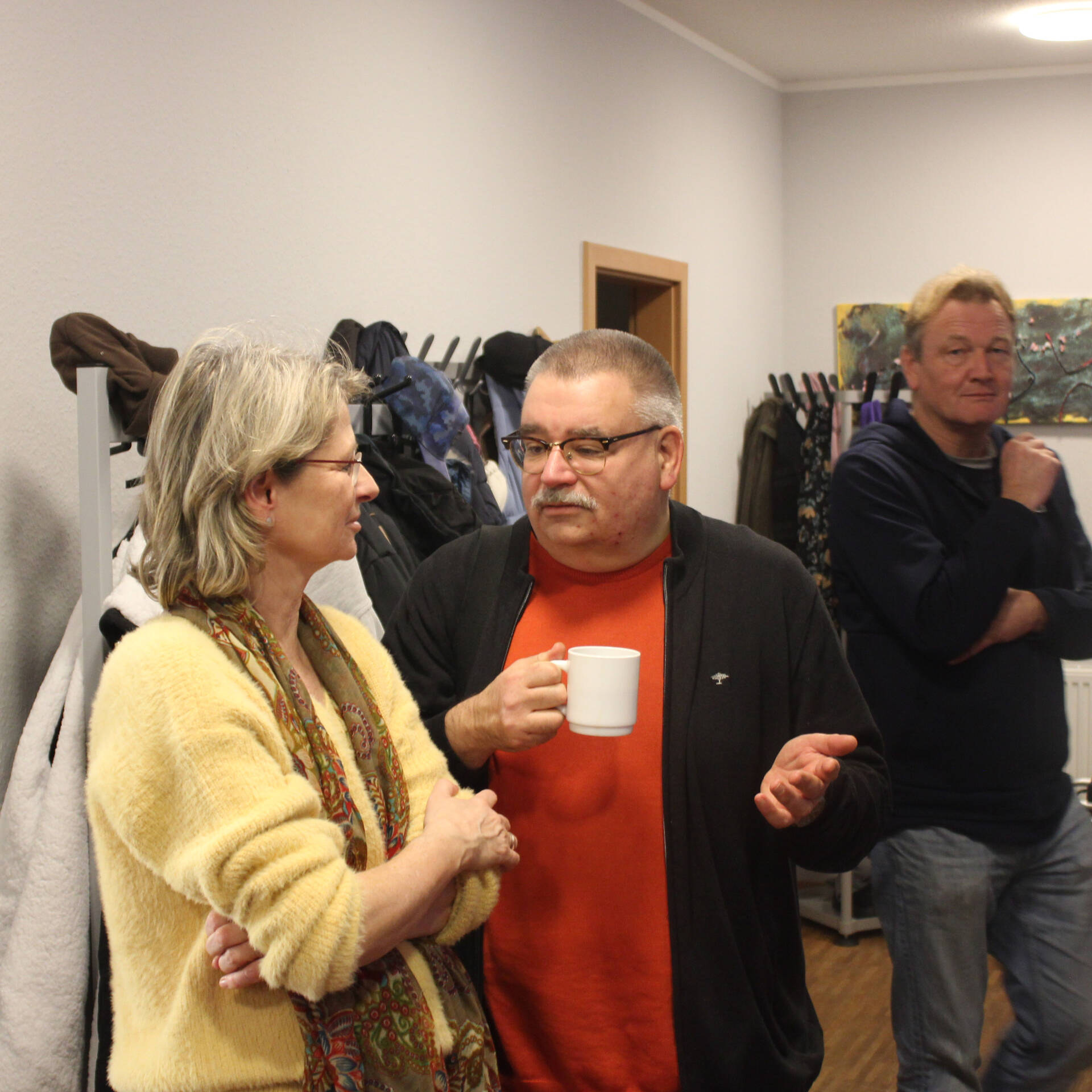 Drei Personen stehen in einem kleinen Raum