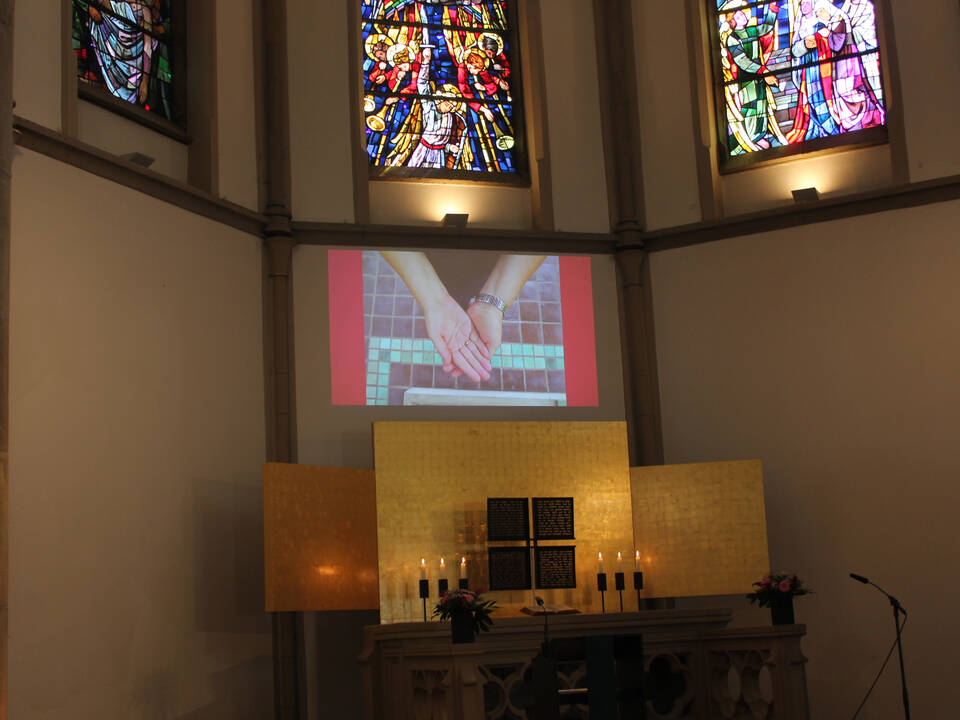 Über dem Altar ist ein Bild mit 2 Händen die sich halten.