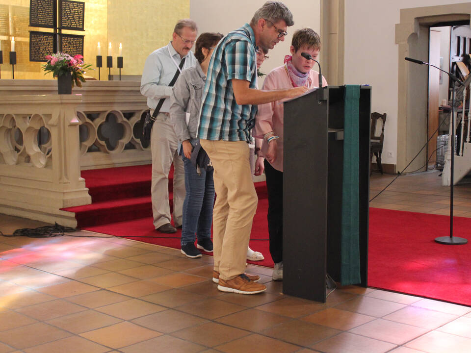 Menschen stehen vor dem Altar und sprechen.