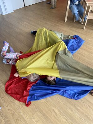 Kinder wickeln sich in ein Schwungtuch ein.
