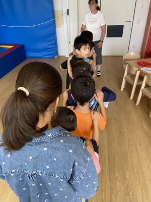 Kinder stellen sich hintereinander auf und legen die Hände auf die Schultern.