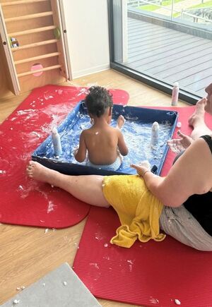 Ein Kind sitzt mit Schaum in einem Becken.