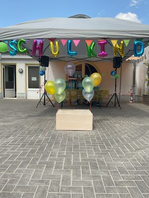 Es hängen Ballons in Form von Buchstabeen an einem Pavillion.