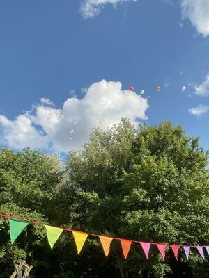 Man sieht Bäume, den Himmel und bunte Fähnchen.