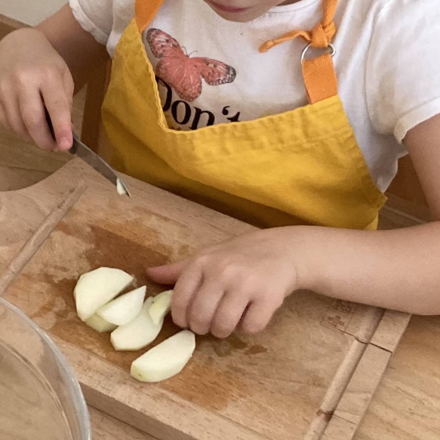 Apfelspalten auf eine Holzbreitt, Kinderhände in einer ein Messer.
