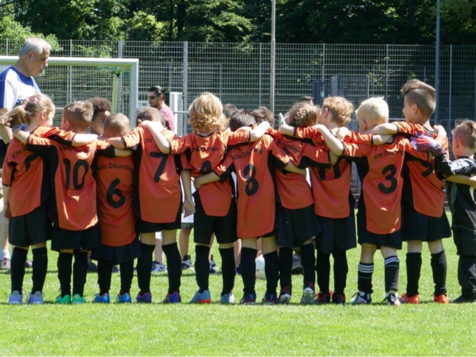 Eine Mannschaft steht mit dem Trainer auf dem Fussballplatz