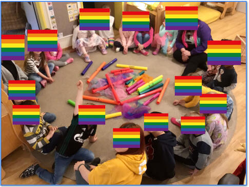 Viele Kinder Kinder sitzen im Kreis auf dem Boden und haben bunte Rohre in der Mitte.