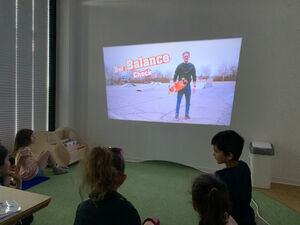 Kinder schauen auf eine Wand wo  etwas angestrahlt wird.