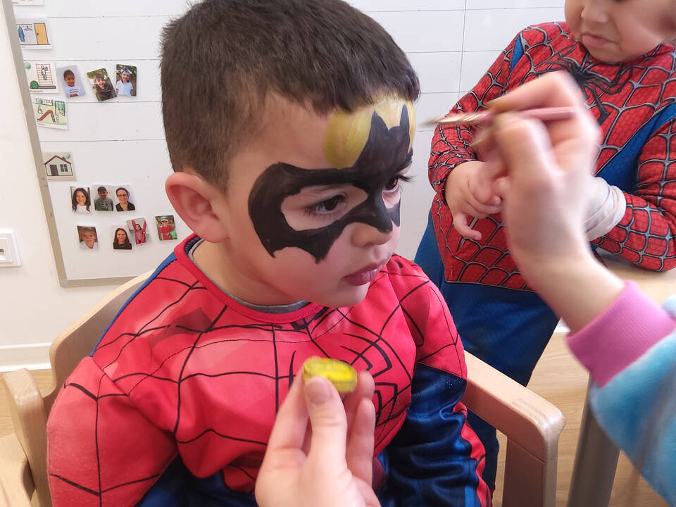 Ein Kind bekommt eine Fledermaus ins Gesicht gemalt.