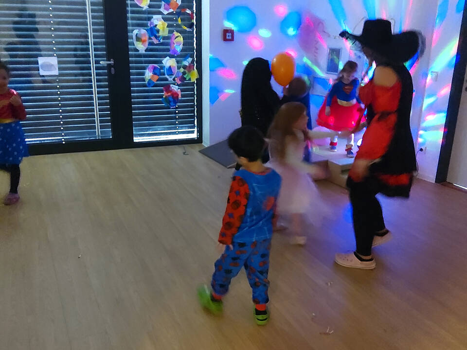 Ein Raum der bunt beleuchtet ist und Kinder tanzen.