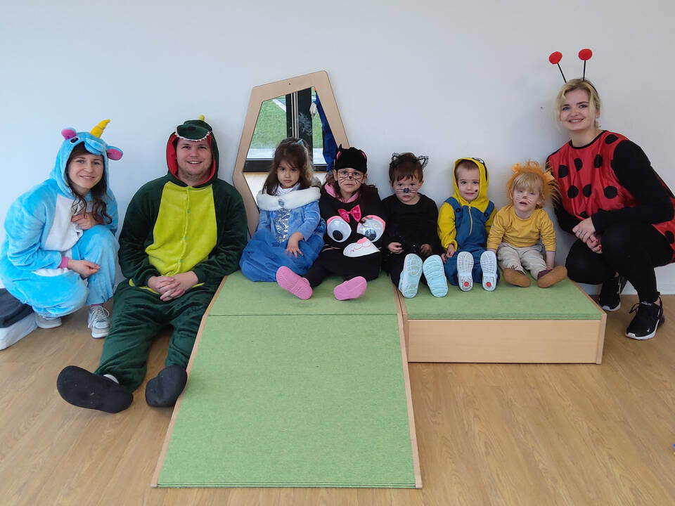 Kinder sitzen auf einem Podest, kostümiert.