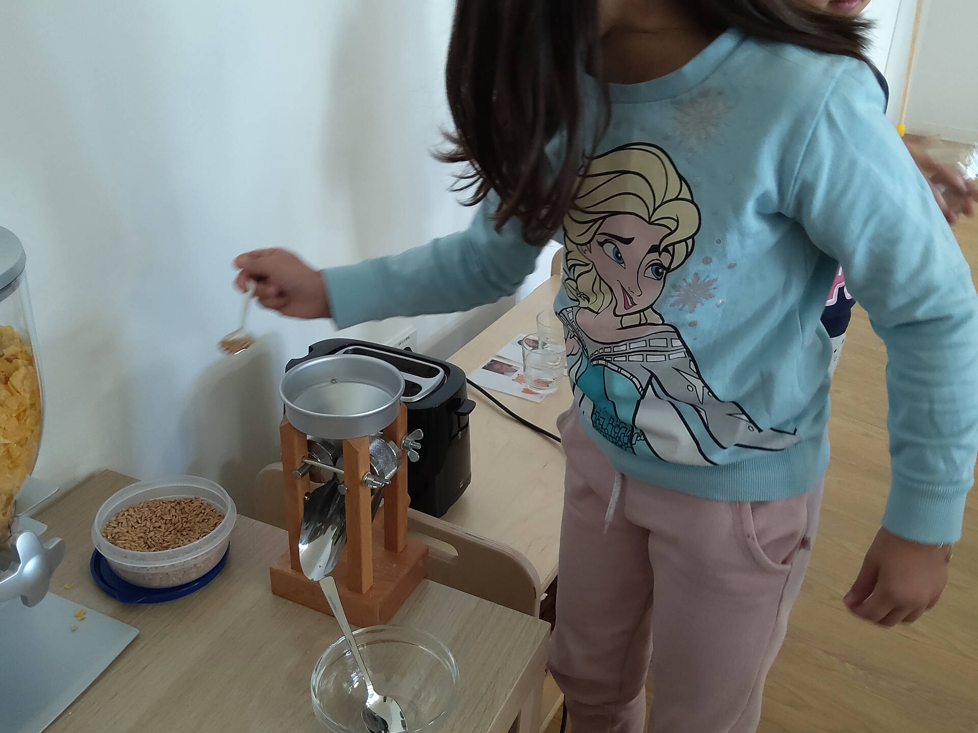 Ein Kind füllt Körner in die Kornquetsche.