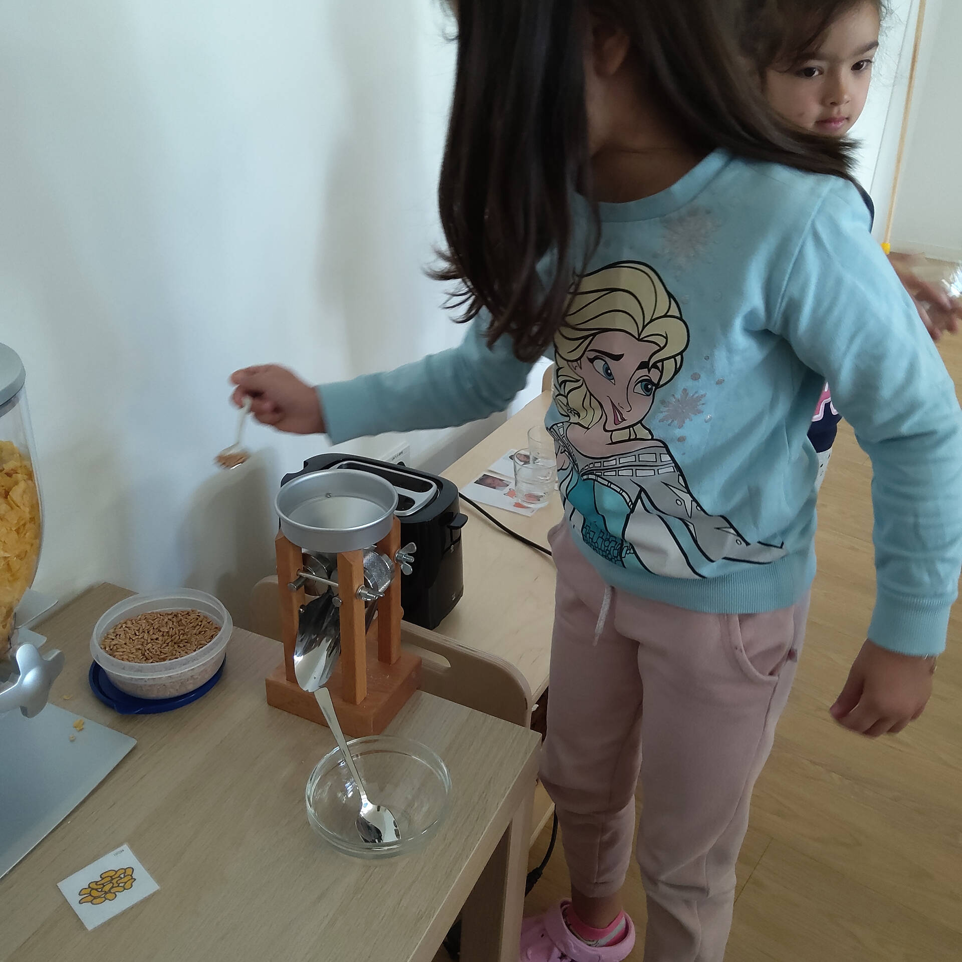 Ein Kind füllt Körner in die Kornquetsche.