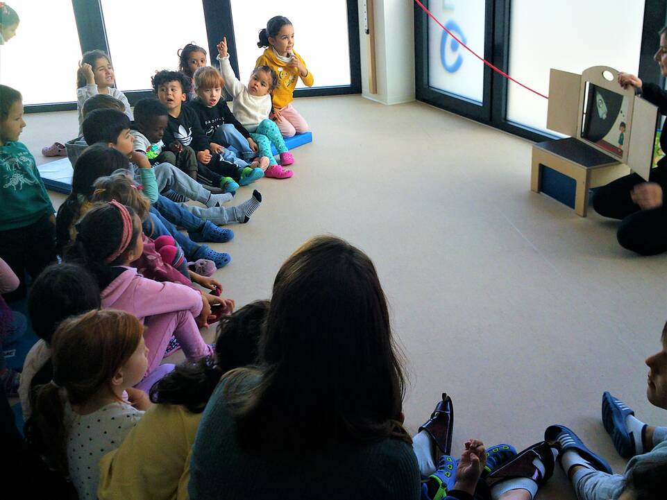 Kinder sitzen auf dem Boden im Halbkreis