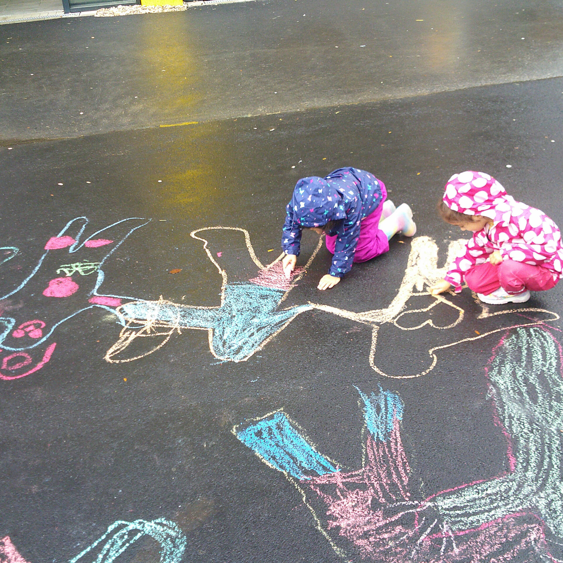 Kinder malen mit Kreide Menschen auf eine Straße.