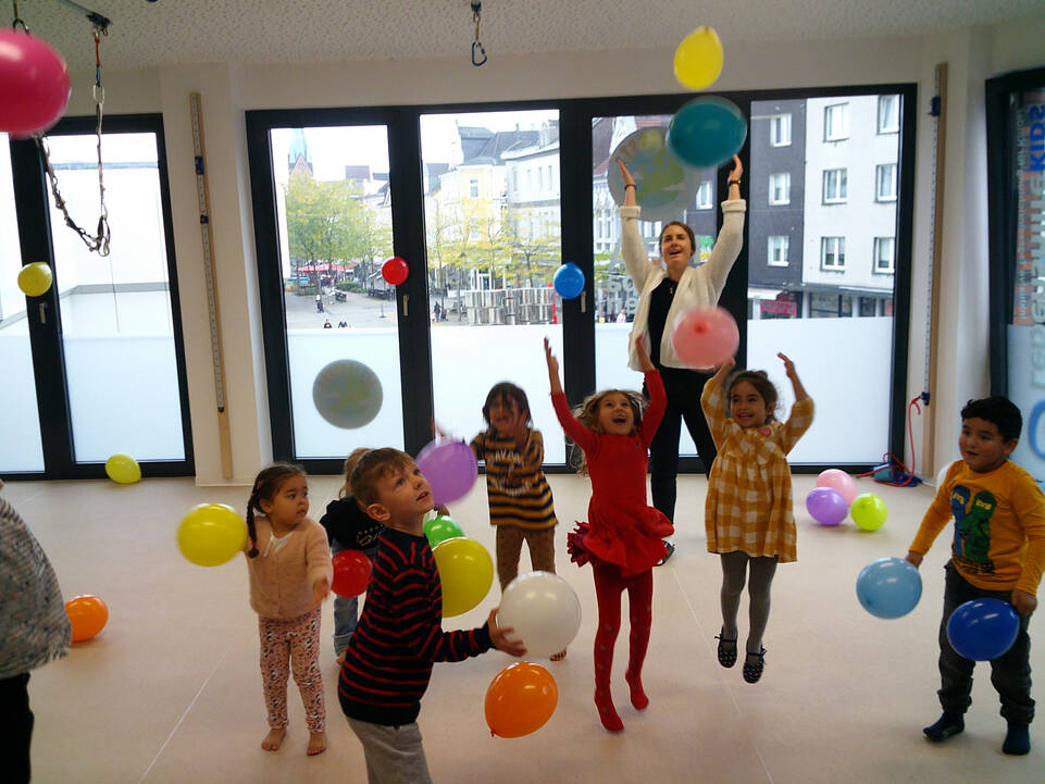 Kinder spielen innen mit Luftballonen.