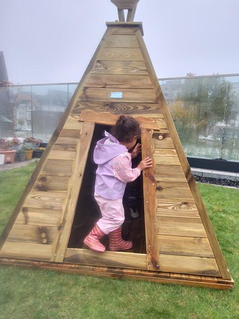 Ein Kind klettert in ein Tipi.