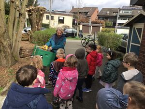 Einige Kinder und eine Frau trägt eine große Kiste.