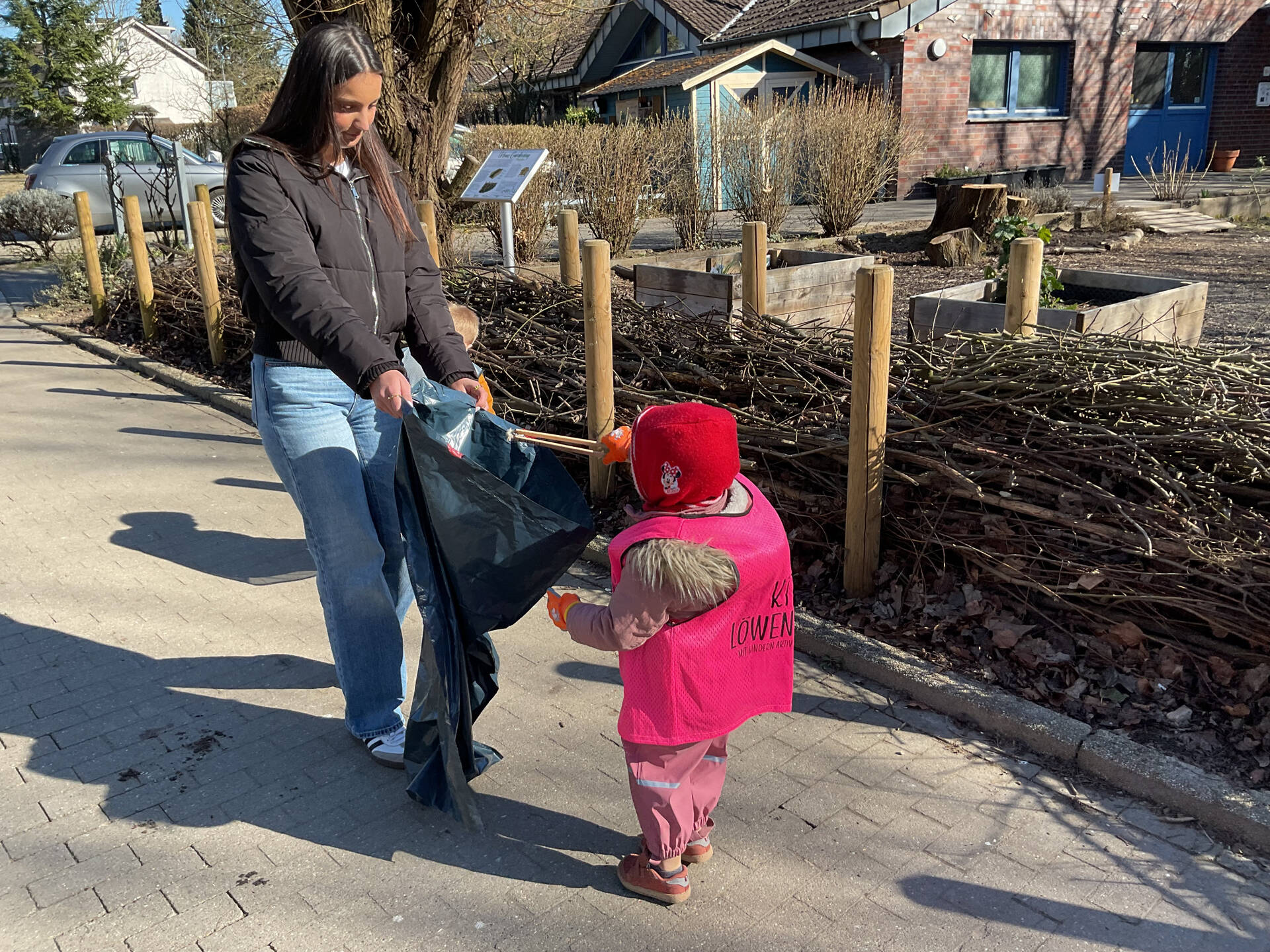 Ein Kind wirft Müll in einen Müllsack.