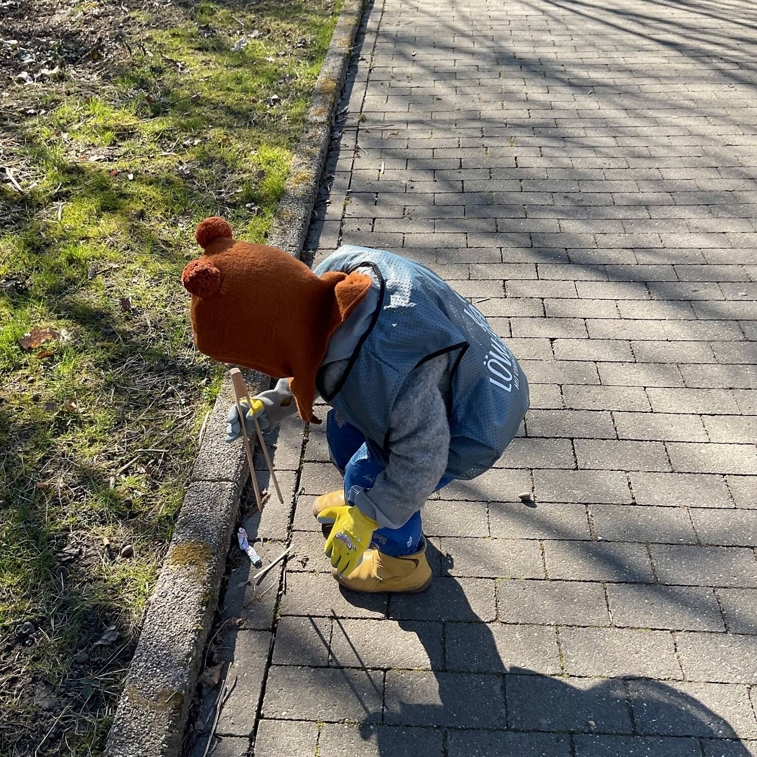 Ein Kind hebt Müll mit einer Zange auf.