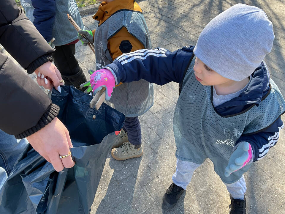 Ein Junge bring Müll in einen Müllsack.