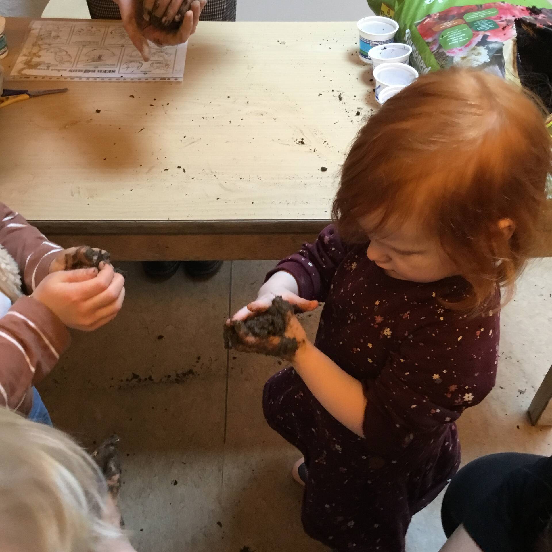 Ein Mädchen formt in den Händen Erde.