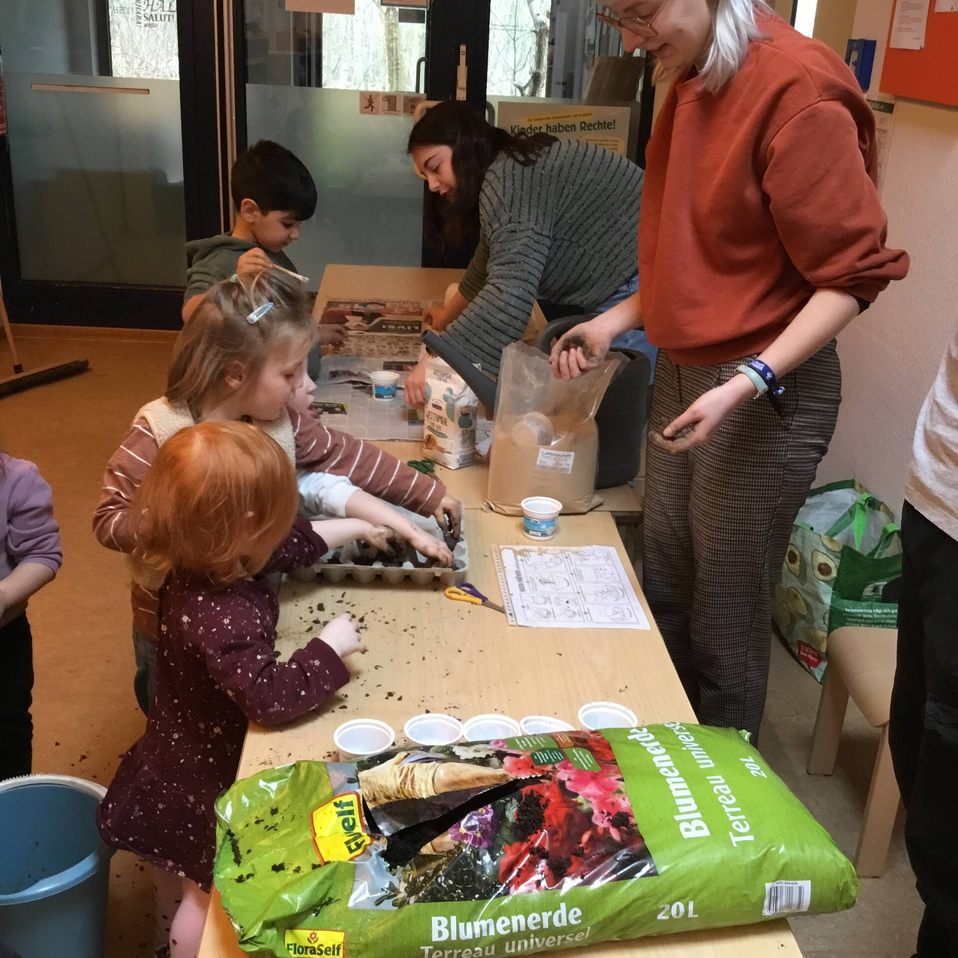 Kinder befüllen Eierkartons mit Erde.