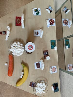Es liegen Nahrungsmittel auf einem Tisch, danebenen liegen Zuckerstücke.