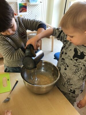 Zwei Kinder mixen etwas in einer Schüssel.