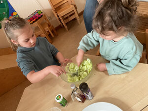 Kinder verrühren einen Gurkensalat.