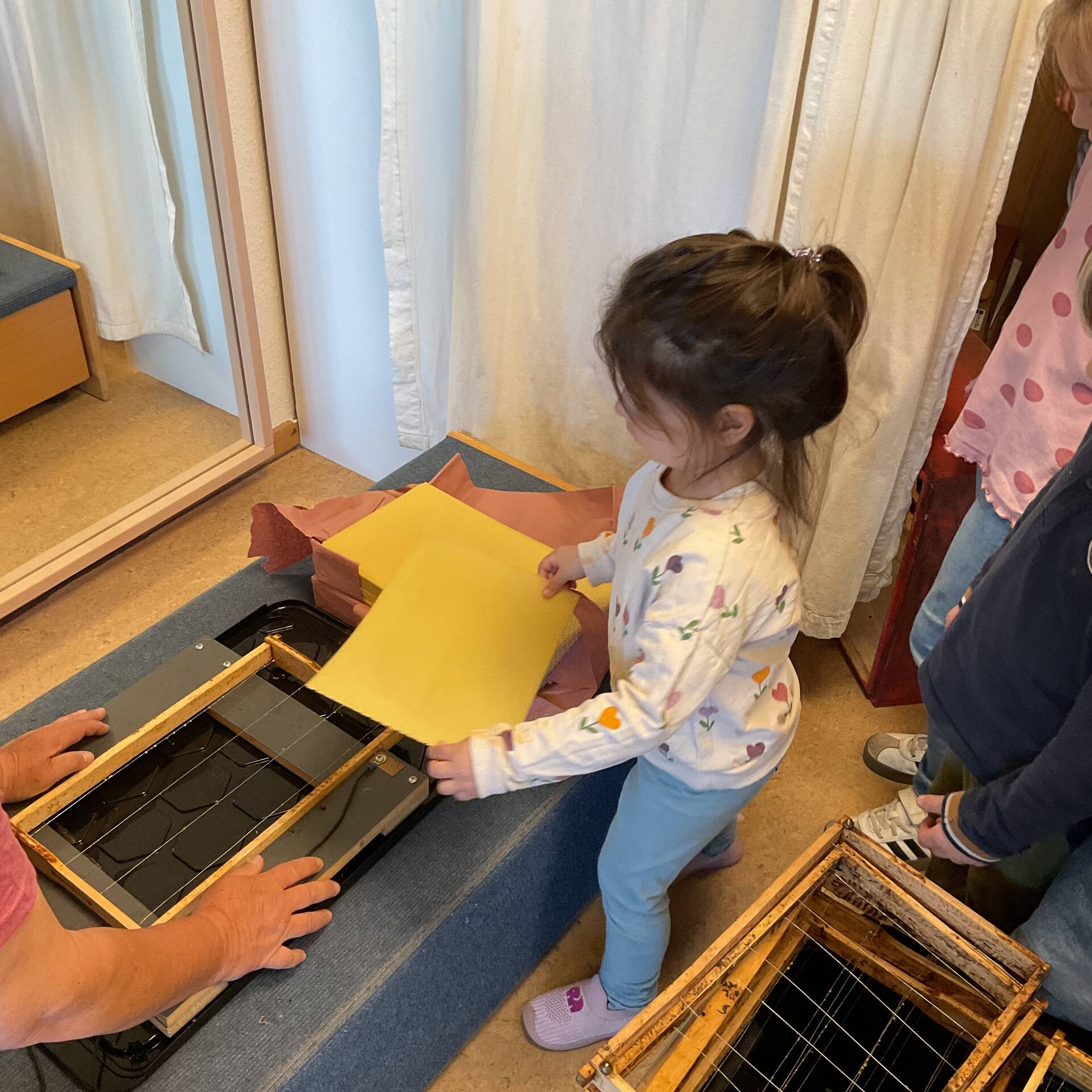 Eine neue Wachsplatte legt ein Kind in den Rahmen.