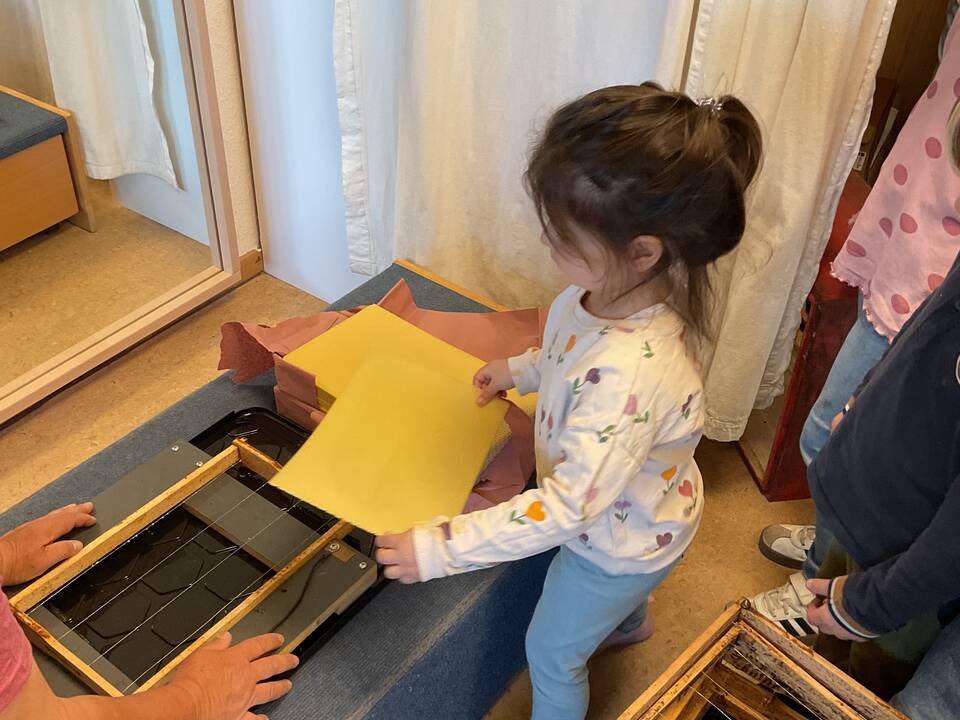 Eine neue Wachsplatte legt ein Kind in den Rahmen.