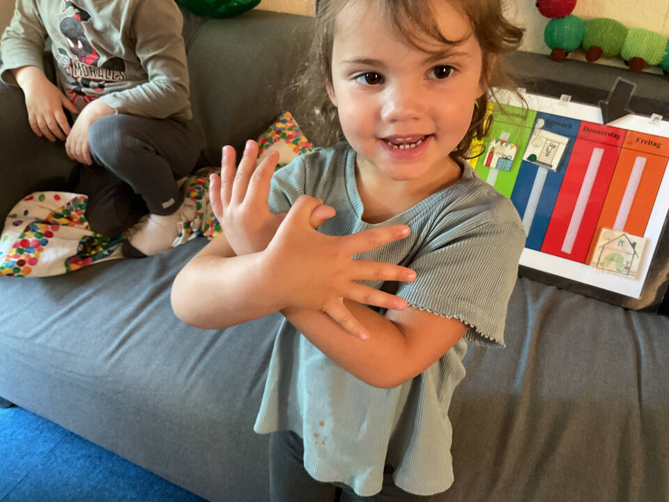 Ein Kind hält seine Arme über Kreuz vor dem Körper