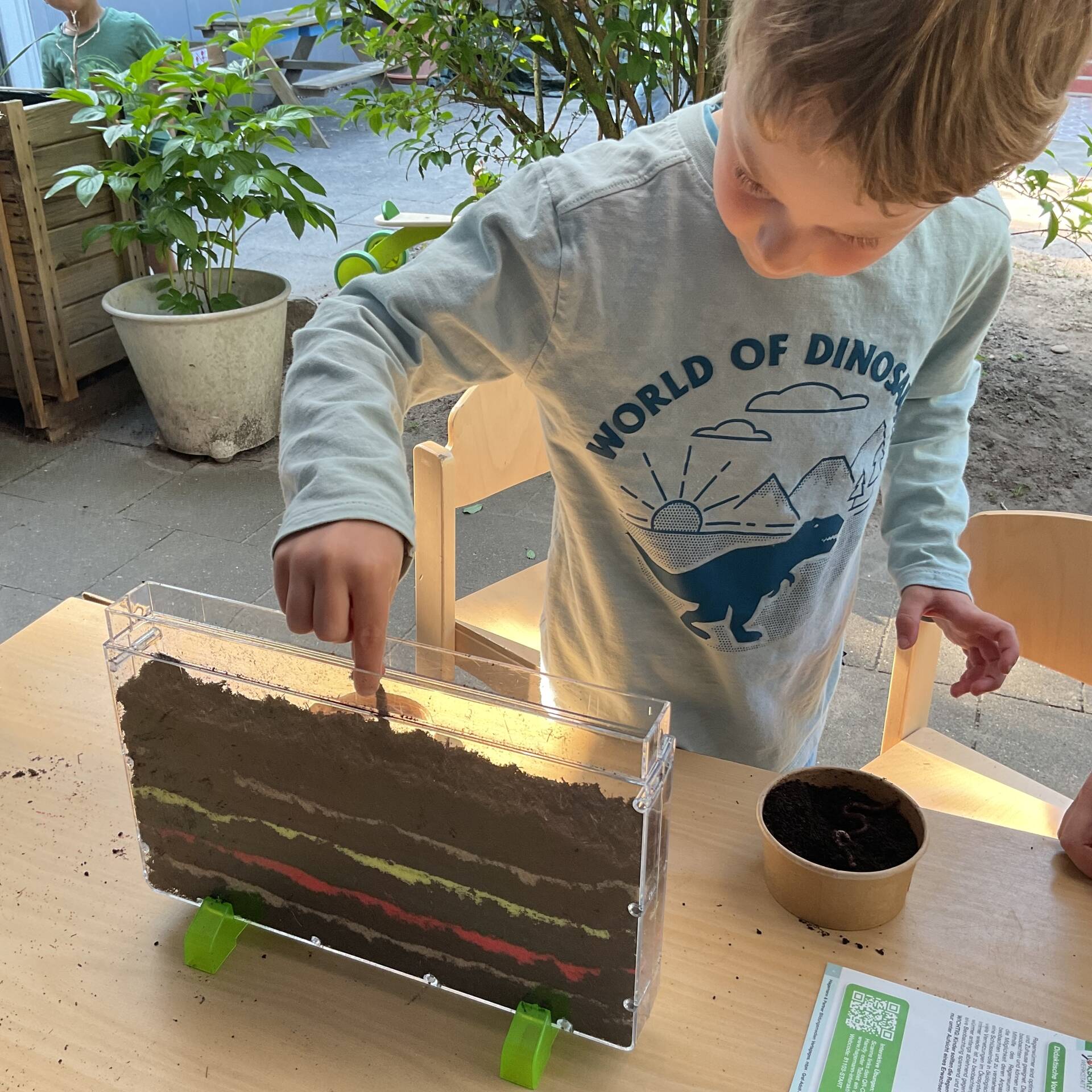 Ein Kind befüllt ein Terrarium.