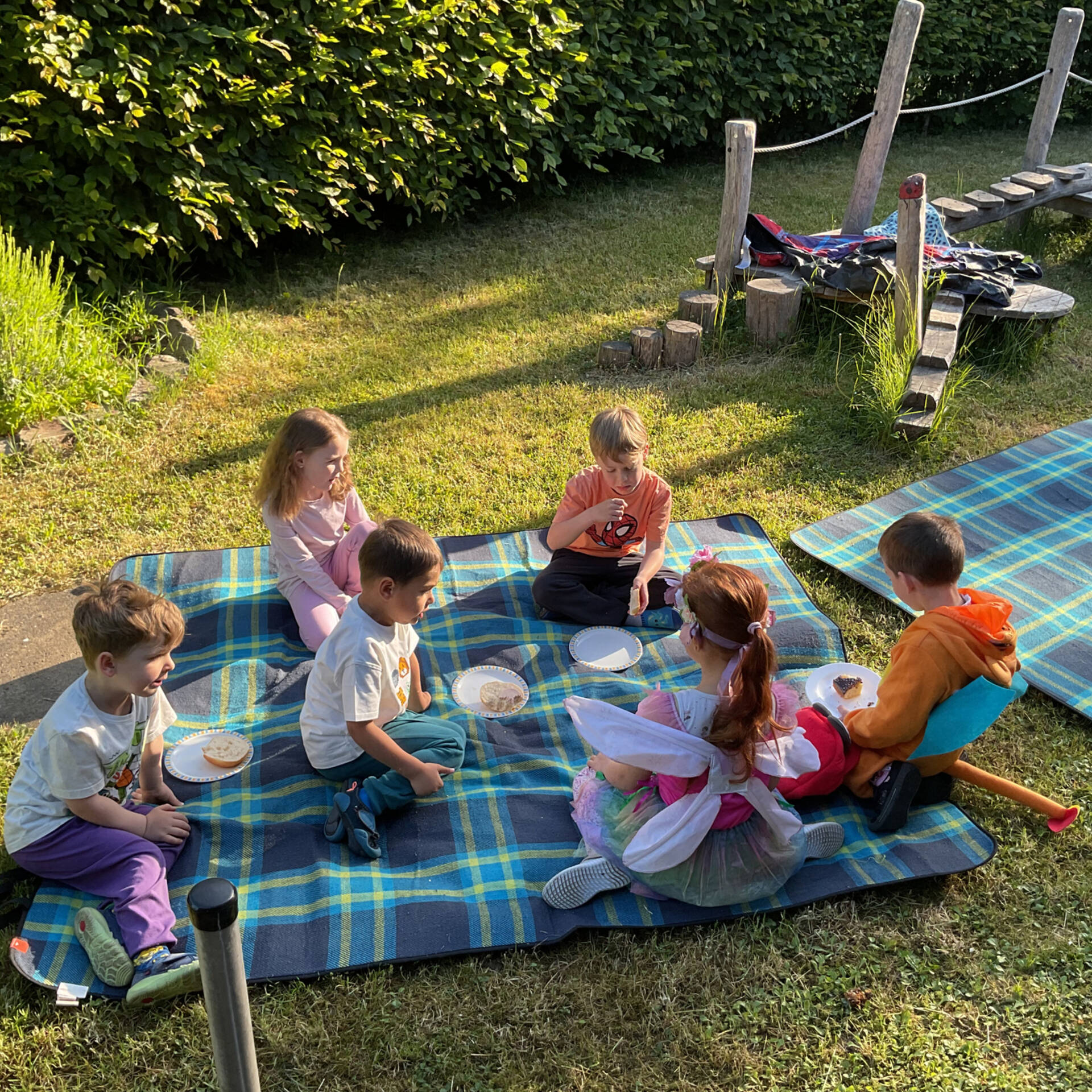 Kinder sitzen auf einer Picknikdecke und essen.