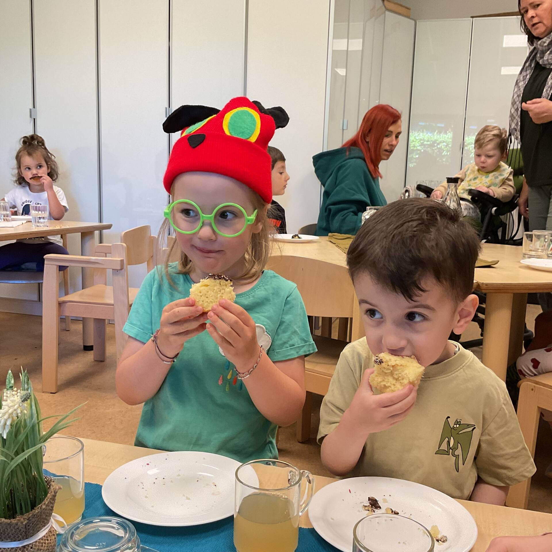 Zwei Kinder sitzen nebeneinander und essen Kuchen.