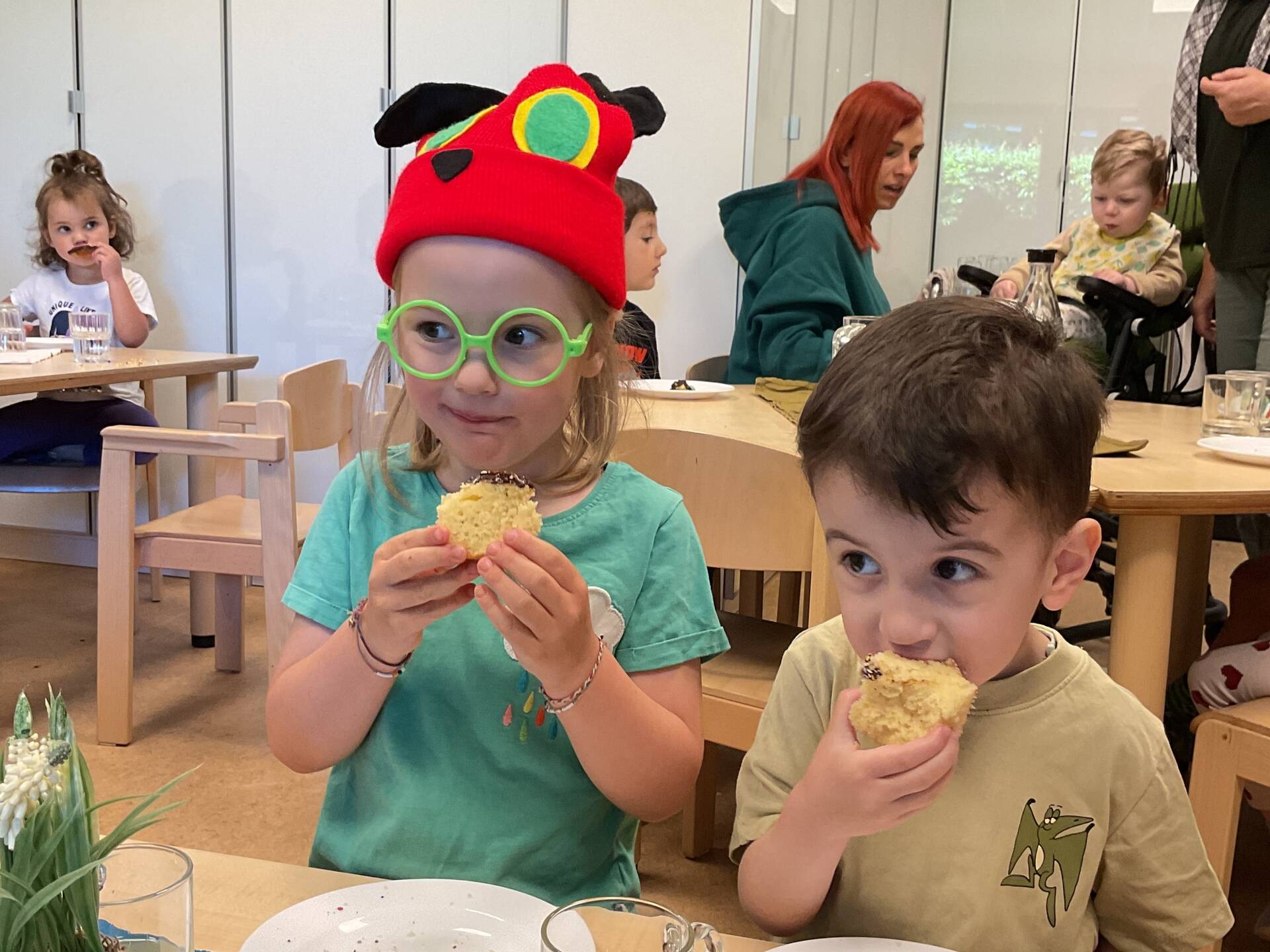 Zwei Kinder sitzen nebeneinander und essen Kuchen.